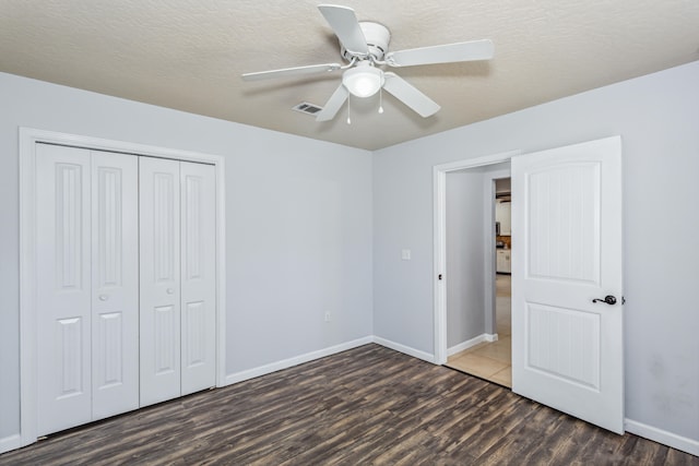 unfurnished bedroom featuring a closet, ceiling fan, a textured ceiling, and dark hardwood / wood-style floors