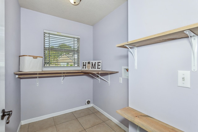 clothes washing area with hookup for a washing machine, a textured ceiling, light tile patterned floors, and hookup for an electric dryer