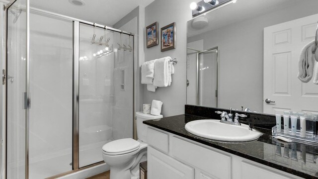 bathroom with walk in shower, vanity, and toilet