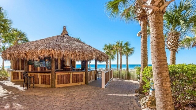 view of community featuring an outdoor bar, a gazebo, a water view, and a patio area