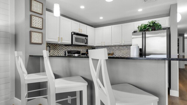 kitchen featuring a breakfast bar area, appliances with stainless steel finishes, kitchen peninsula, and white cabinetry