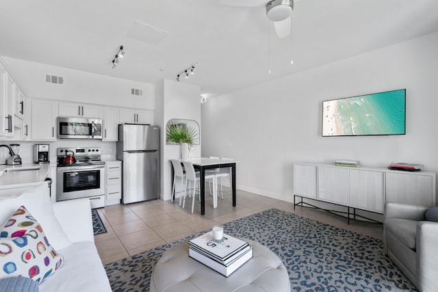 tiled living room featuring rail lighting, ceiling fan, and sink