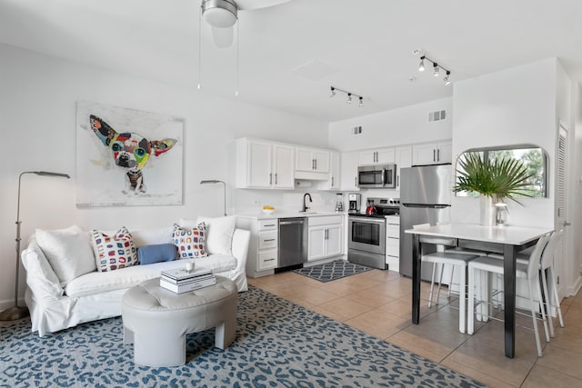 living room featuring tile patterned flooring, ceiling fan, track lighting, and sink