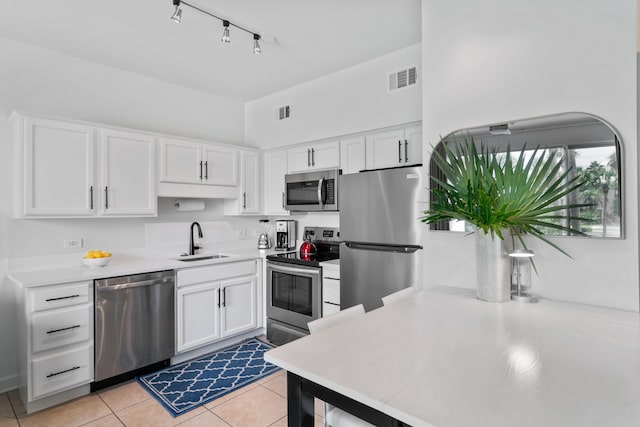 kitchen featuring white cabinetry, sink, light tile patterned floors, and stainless steel appliances