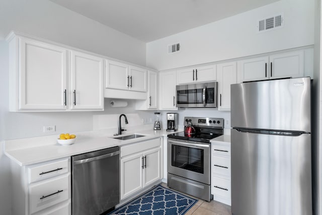 kitchen with sink, light tile patterned floors, stainless steel appliances, and white cabinets