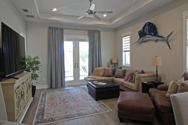 living room featuring french doors, a raised ceiling, hardwood / wood-style floors, and ceiling fan