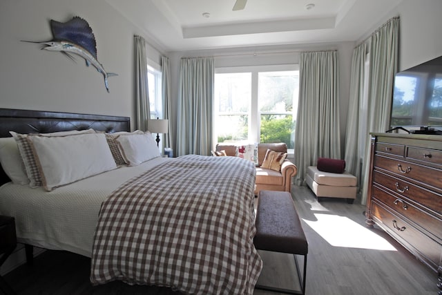 bedroom with wood-type flooring, a raised ceiling, and ceiling fan