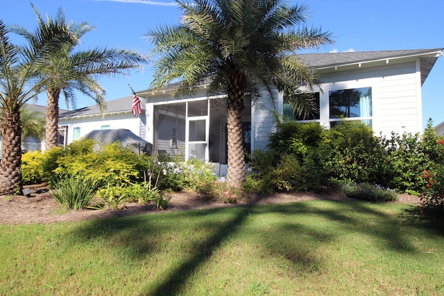 view of side of property featuring a yard and a sunroom