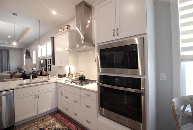 kitchen featuring wall chimney exhaust hood, stainless steel appliances, white cabinets, and sink