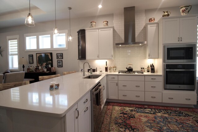 kitchen with sink, white cabinetry, wall chimney exhaust hood, decorative backsplash, and appliances with stainless steel finishes