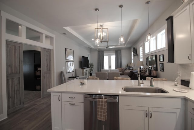 kitchen with a raised ceiling, stainless steel dishwasher, sink, and white cabinets