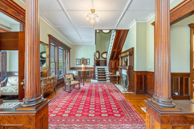 sitting room featuring ornamental molding, decorative columns, and wooden walls