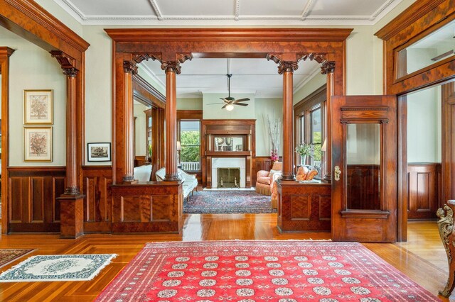 entryway with ornate columns, ceiling fan, and light hardwood / wood-style flooring