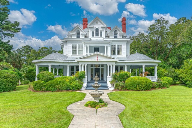 victorian house featuring a porch and a front lawn