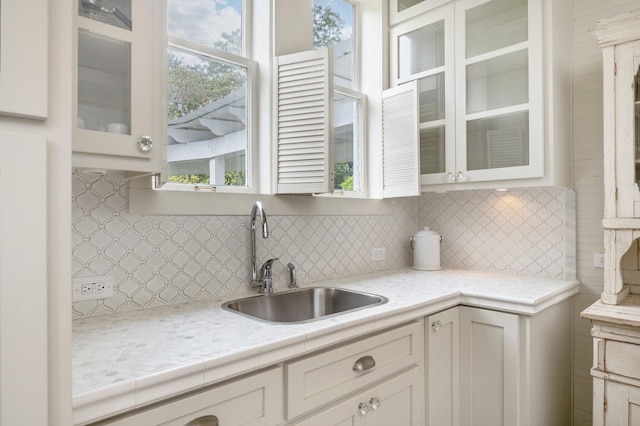 kitchen with decorative backsplash, sink, and white cabinetry