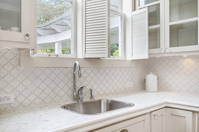 kitchen featuring tasteful backsplash, plenty of natural light, sink, and white cabinets