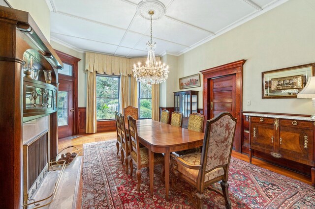 dining area featuring a premium fireplace, crown molding, hardwood / wood-style floors, and an inviting chandelier