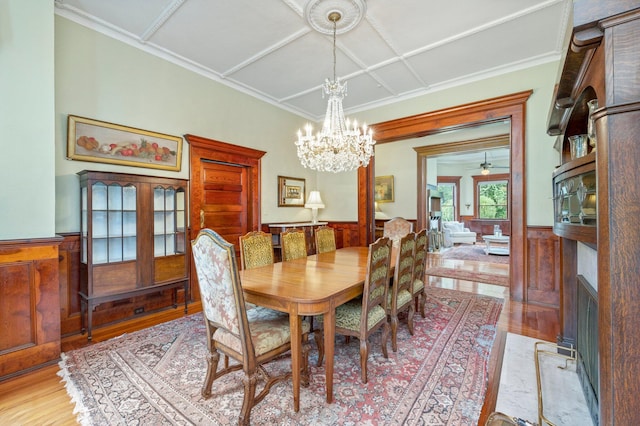 dining space featuring coffered ceiling, ceiling fan with notable chandelier, light hardwood / wood-style flooring, and crown molding