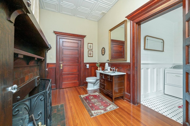 bathroom with wood-type flooring, vanity, toilet, and washer / dryer