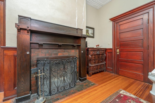 interior space featuring wood walls, wood-type flooring, and a brick fireplace