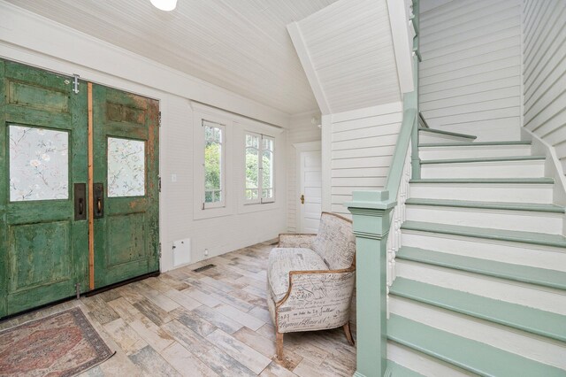 entrance foyer featuring light wood-type flooring and wooden walls