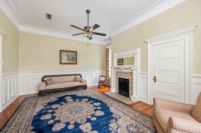 sitting room featuring ornamental molding, ceiling fan, a tile fireplace, and light hardwood / wood-style flooring