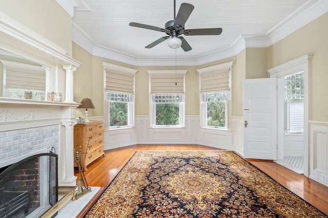 interior space with a brick fireplace, light hardwood / wood-style flooring, crown molding, and ceiling fan