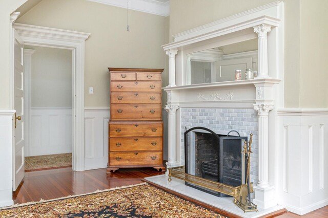 living room featuring a brick fireplace, hardwood / wood-style flooring, and crown molding