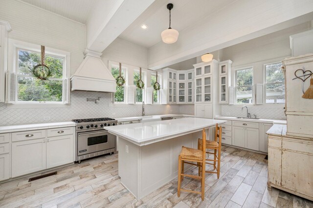 kitchen with decorative backsplash, hanging light fixtures, a center island, and premium stove