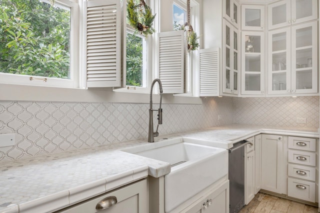 kitchen featuring a wealth of natural light, stainless steel dishwasher, backsplash, and white cabinets