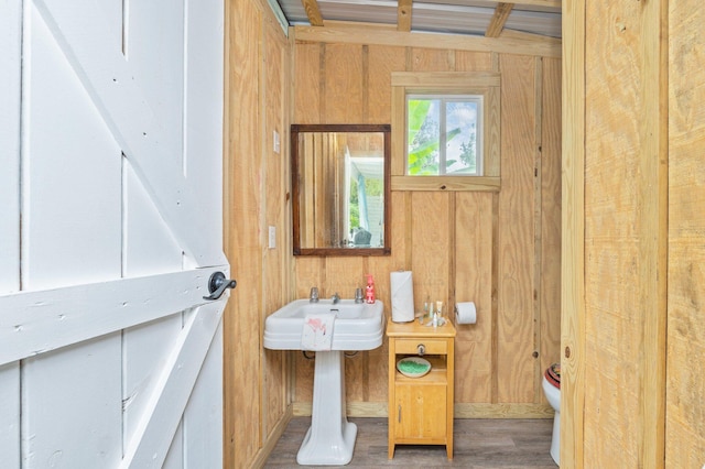 bathroom featuring hardwood / wood-style flooring, wood walls, and toilet