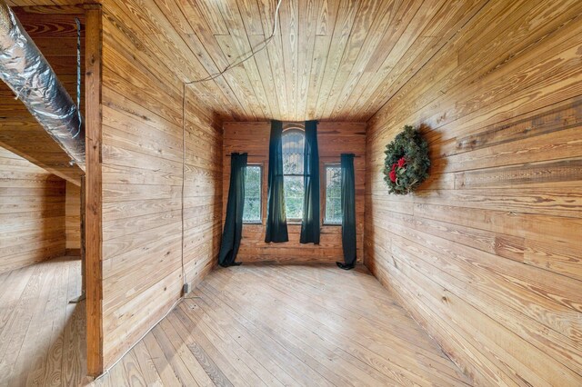 hall with wood walls, wood-type flooring, and wooden ceiling