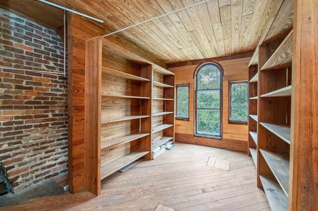 interior space featuring brick wall, light hardwood / wood-style flooring, wood walls, and wooden ceiling