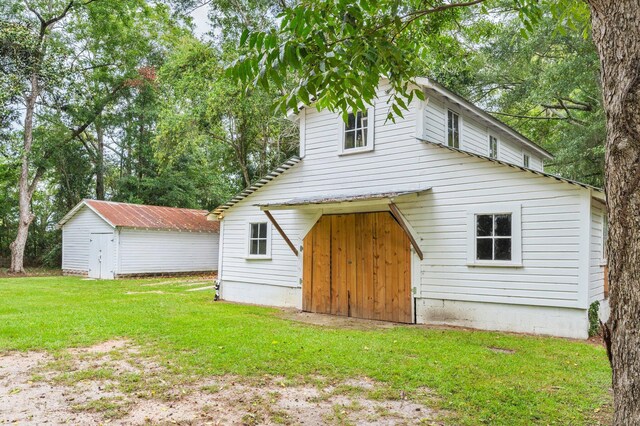 rear view of property with a yard and a storage unit