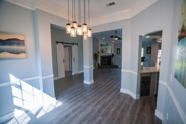 dining space with a barn door, ornamental molding, dark hardwood / wood-style flooring, and ceiling fan