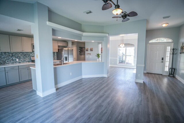 kitchen with ceiling fan, stainless steel fridge, decorative light fixtures, backsplash, and dark hardwood / wood-style flooring