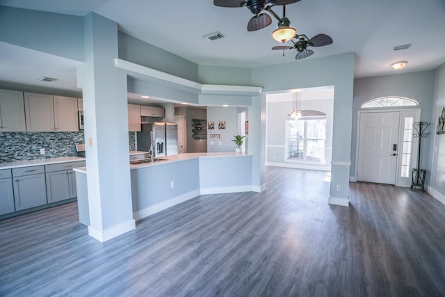 kitchen featuring ceiling fan, gray cabinetry, stainless steel fridge with ice dispenser, dark hardwood / wood-style flooring, and decorative backsplash