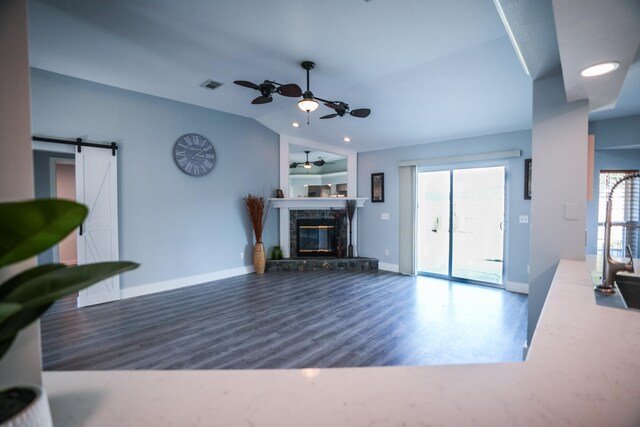 living room featuring lofted ceiling, a barn door, ceiling fan, and dark wood-type flooring