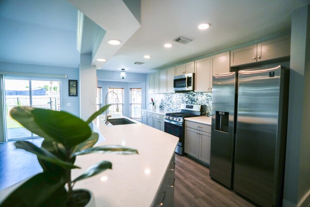 kitchen featuring stainless steel appliances, tasteful backsplash, dark wood-type flooring, sink, and gray cabinets