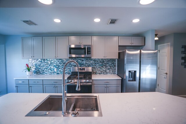 kitchen with gray cabinetry, sink, stainless steel appliances, and backsplash