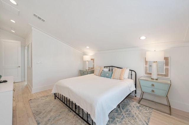 bedroom featuring light hardwood / wood-style floors, crown molding, and vaulted ceiling