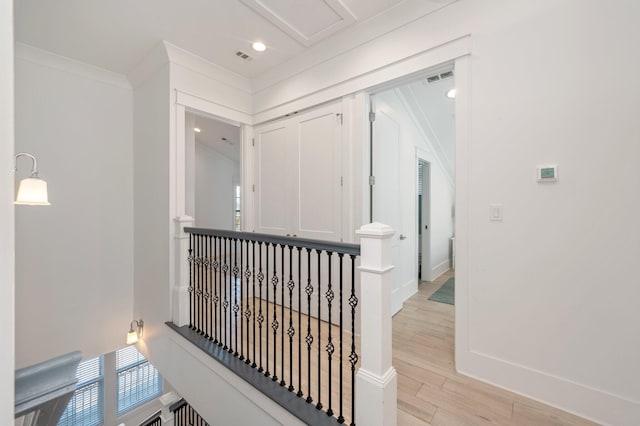 corridor with light wood-type flooring and crown molding