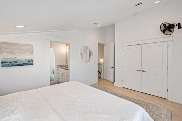 bedroom with ensuite bathroom, ornamental molding, vaulted ceiling, light hardwood / wood-style flooring, and a closet