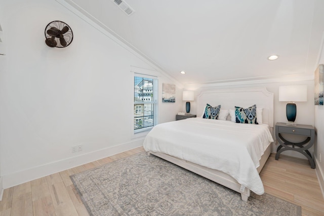 bedroom featuring ornamental molding, lofted ceiling, and light wood-type flooring