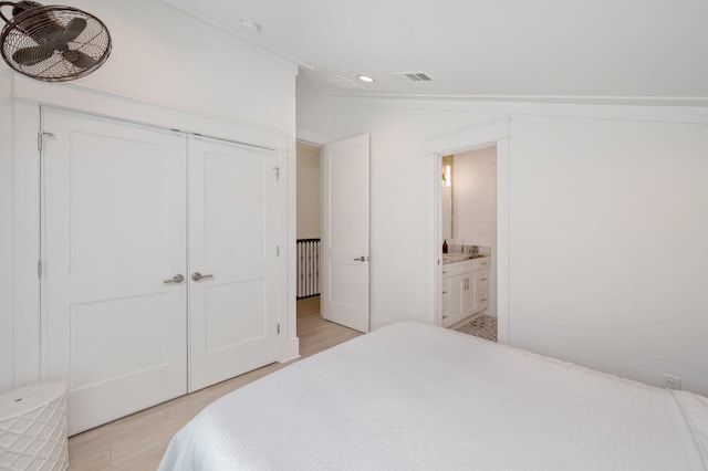 bedroom with ensuite bath, light hardwood / wood-style floors, crown molding, and a closet