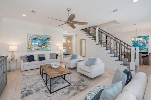 living room featuring ornamental molding, ceiling fan with notable chandelier, and light wood-type flooring