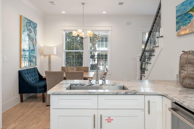 kitchen with white cabinets, light hardwood / wood-style floors, a notable chandelier, and sink