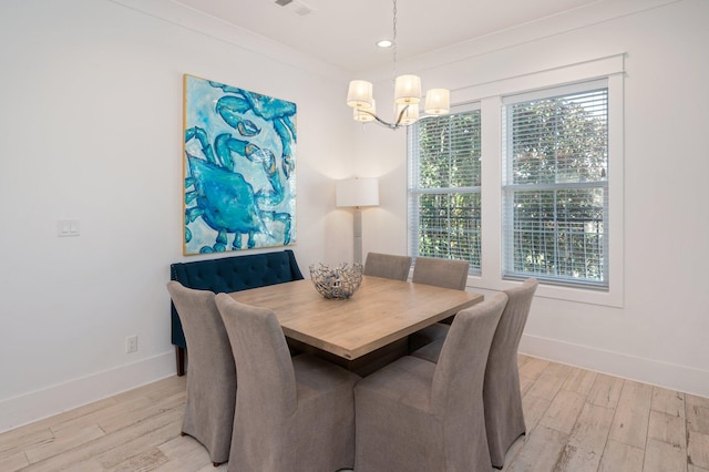 dining space with light hardwood / wood-style flooring, ornamental molding, and a notable chandelier