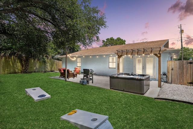 back house at dusk featuring a pergola, a jacuzzi, a yard, and a patio