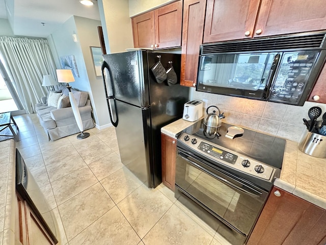 5002 S Sandestin Blvd # 6322, Miramar Beach, FL 32550 - kitchen with black appliances, decorative backsplash, light tile patterned floors, light countertops, and brown cabinets
